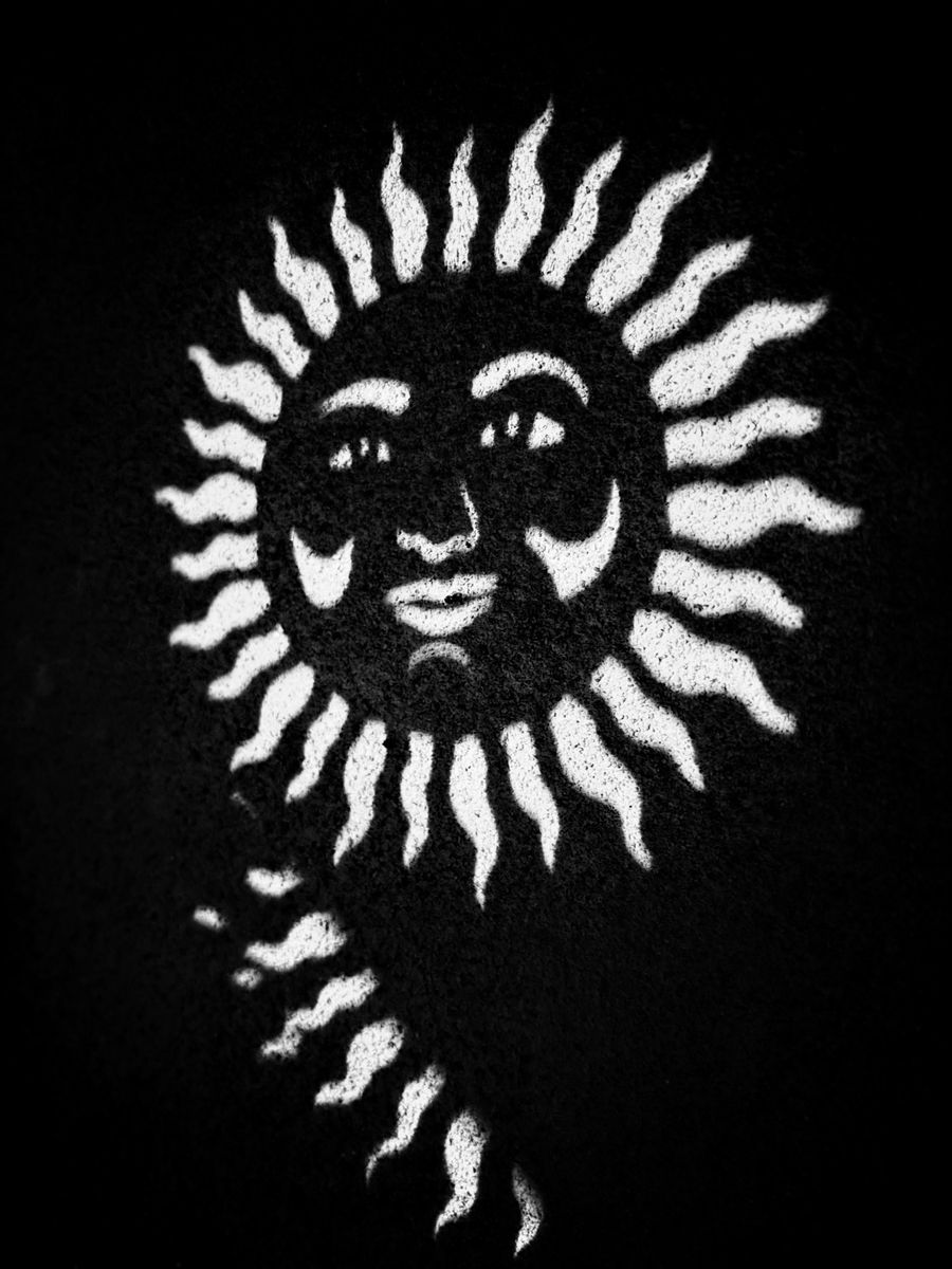 The sun stencil's shadow on a rough wall: a dark disk with bright rays and features.